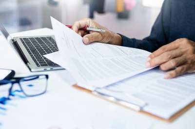 Person mit Dokumenten und Laptop