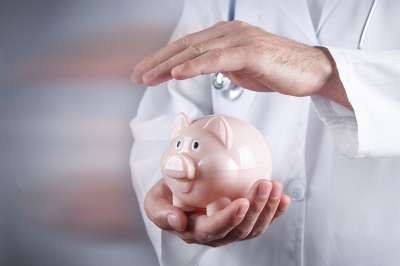 Arzt hält Hand über Sparschwein